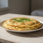 Готовый пышный омлет с зеленью на тарелке